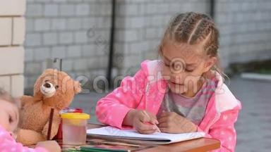 七岁的女孩热情地在相册上画一支铅笔，和他的妹妹在街上画画
