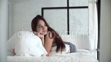 美丽的女人躺在舒适的床上拥抱枕头
