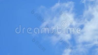一架遥远的飞机从高空飞过，在多云的蓝天上留下一个喷气式飞机的轨迹。 风