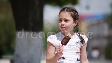 在阳光明媚的夏日，可爱的小女孩在公园里吃冰淇淋。