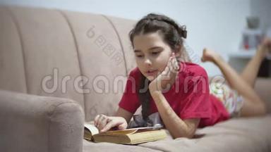 十几岁的女孩躺在沙发上<strong>看书</strong>。 躺在沙发上<strong>看书</strong>的女孩