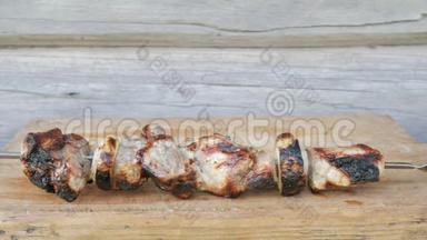 烧烤中的熟肉放在木板上.. 粗糙，轻微烧焦的碎片.. 背景木墙