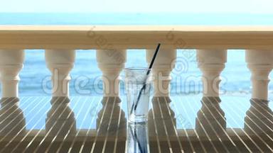 餐厅桌上放着一杯冰的水，俯瞰大海。 在海浪的背景下。 复制空间。