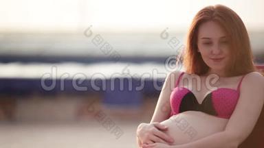 红头孕妇穿着泳衣在泳池边晒日光浴。 夏日心情