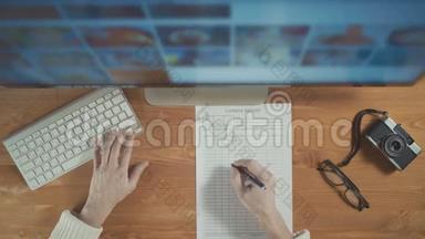 摄影师使用显示器和键盘从电脑显示器中选择照片。 顶部视图