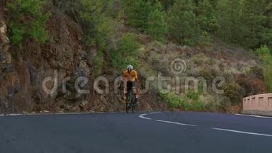 一个骑着运动型公路自行车的人在山上的公路上骑车