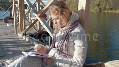 秋河附近的桥上的女人读一<strong>本书</strong>，吃一个苹果