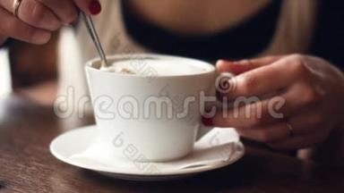 年轻快乐的女人喝咖啡，<strong>用勺子</strong>搅拌牛奶泡沫