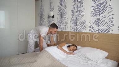 年轻人把早餐放在床上，而他惊讶的女朋友穿着睡衣坐在床上