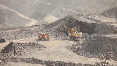 挖土机和翻斗车在采石场，大型黄色挖掘机将矿石装入翻斗车，工业外部