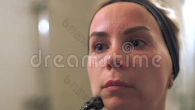 年轻的女人用真皮滚筒做脸。 滚筒、微针、中间疗法