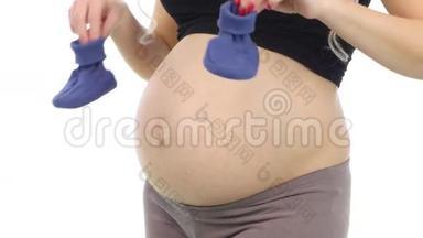 孕妇抱着蓝色的婴儿罩到她的腹部等待婴儿，白色，特写