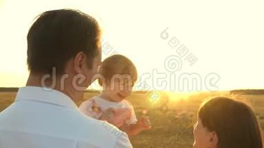 日落时分，爸爸和妈妈和她的女儿抱在怀里散步。 一家人在日落时带着一个孩子散步。 有女儿的父亲