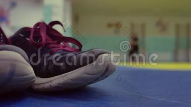 运动鞋在健身房的垫子上。 在后台跑步女孩热身模糊背景概念运动室内