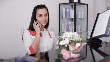 一位美丽的微笑<strong>护士</strong>在办公桌<strong>站</strong>边打电话的肖像。