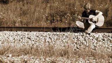 一位<strong>左撇子</strong>、长发吉他手坐在铁路上演奏