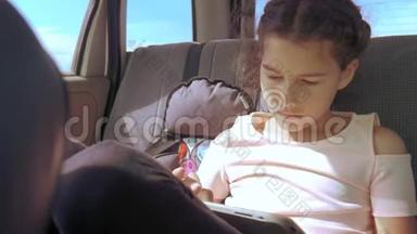 小女孩坐在车里，带着平板电脑去美国旅行，生活方式德克萨斯州。 汽车概念旅行运输女孩