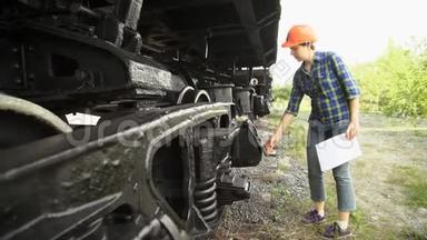 一个年轻的女<strong>火车司机</strong>检查货车的车轴箱。