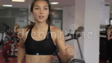 年轻女子在室内运动俱乐部跑步机上跑步。