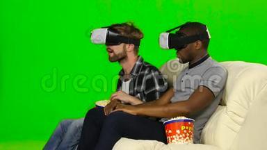 穿着VR面具的男人用爆米花看电影。 绿色屏幕