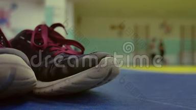 运动鞋在健身房的垫子上。 背景中跑女孩热身模糊背景概念室内运动