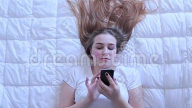 女孩在躺在床上的<strong>手机</strong>上<strong>输入</strong>信息