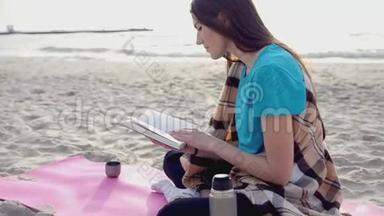 年轻女子在沙滩上看书，<strong>喝</strong>热茶或<strong>热水</strong>瓶里的咖啡