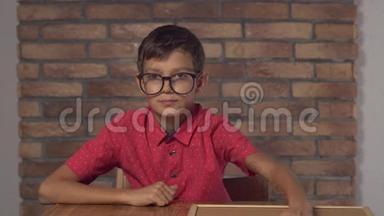 坐在书桌前的孩子拿着一张挂图，背景是红砖墙上的刻字库