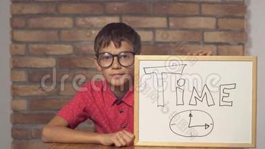 坐在书桌前的孩子拿着一张挂图，上面写着红色砖墙上的刻字时间