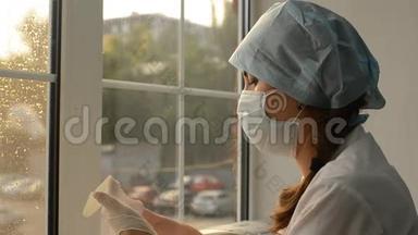戴着口罩的女医生在窗户的背景上戴上橡胶手套