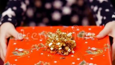 用一个金色的蝴蝶结，用一个漂亮的彩色纸包装着一个圣诞礼物，两只孩子的手紧紧地握着