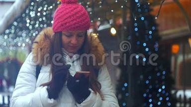 年轻女子微笑着面对冬天的城市。 使用电话