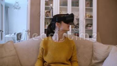漂亮的年轻女子坐在客厅的沙发上，使用VR耳机。 4K