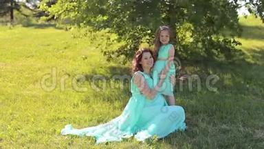一个怀孕的女孩和她的女儿在公园穿裙子