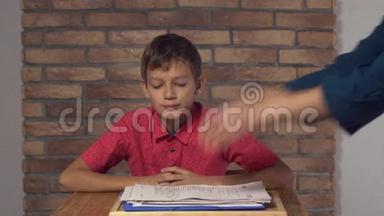 坐在办公桌前的孩子拿着一张挂图，背景红砖墙上有刻字的工作人员。
