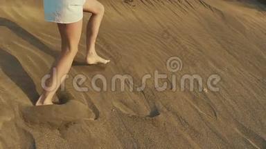 女人在沙丘上逃跑。 沙子上的<strong>脚印</strong>。 <strong>沙漠</strong>日落。 动作缓慢。