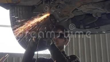 带眼镜切割的机械师在车库用磨床磨损汽车零件