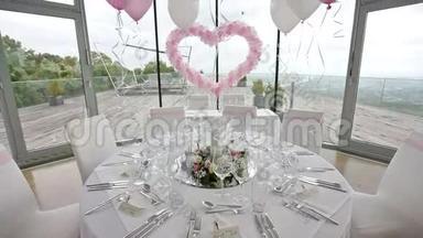 桌子上摆着客人。 豪华婚礼大厅装饰着粉红色的气球和鲜花