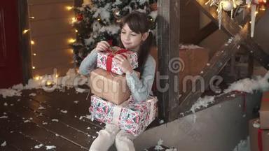 圣诞节或新年。 小女孩手里拿着一个盒子，手里拿着礼物，狡猾地微笑着。 孩子收到了许多礼物