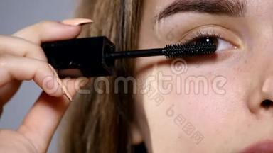 面部化妆。 年轻的深色女人用黑色睫毛膏为她的长睫毛画上一张特写镜头。 4K