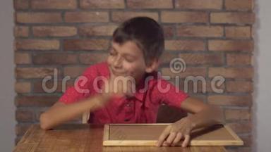 坐在办公桌前的孩子拿着一张<strong>挂图</strong>，在背景红砖墙上醒来。