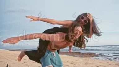 迷人的年轻和精力充沛的夫妇在海滩上玩得很开心。 女人骑着一个<strong>男人</strong>笑。 海洋<strong>夏季</strong>