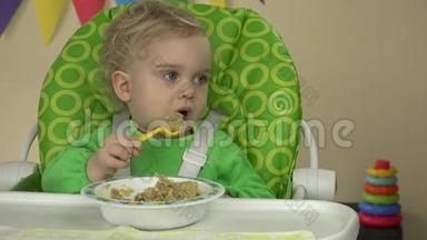 快乐的孩子坐在椅子上用勺子吃美味的<strong>儿童食品</strong>