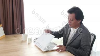 亚洲男人在完成他的笔记本电脑工作后走出框架。