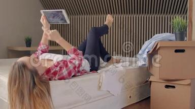 女人躺在床上，用<strong>数码</strong>平板电脑，而不是在新<strong>家</strong>拆箱