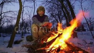有胡子的人在冬天的炉火旁暖手。 游客晚上篝火。