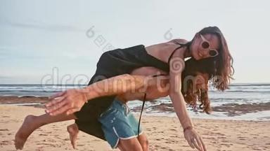 迷人的年轻和精力充沛的夫妇在海滩上玩得很开心。 女人骑着一个<strong>男人</strong>笑。 海洋<strong>夏季</strong>