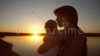 妈妈在日落时抱着孩子在太阳的怀抱里。 慢动作。