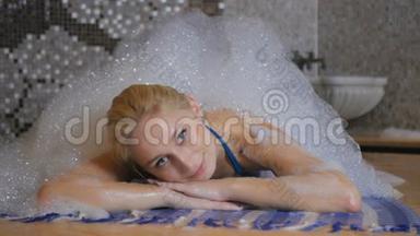美丽的女孩在土耳其浴室的泡沫下放松