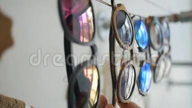 年轻的白人少女在购物台上选择复古太阳镜。 玻璃中美丽的镜面反射。 高清高清